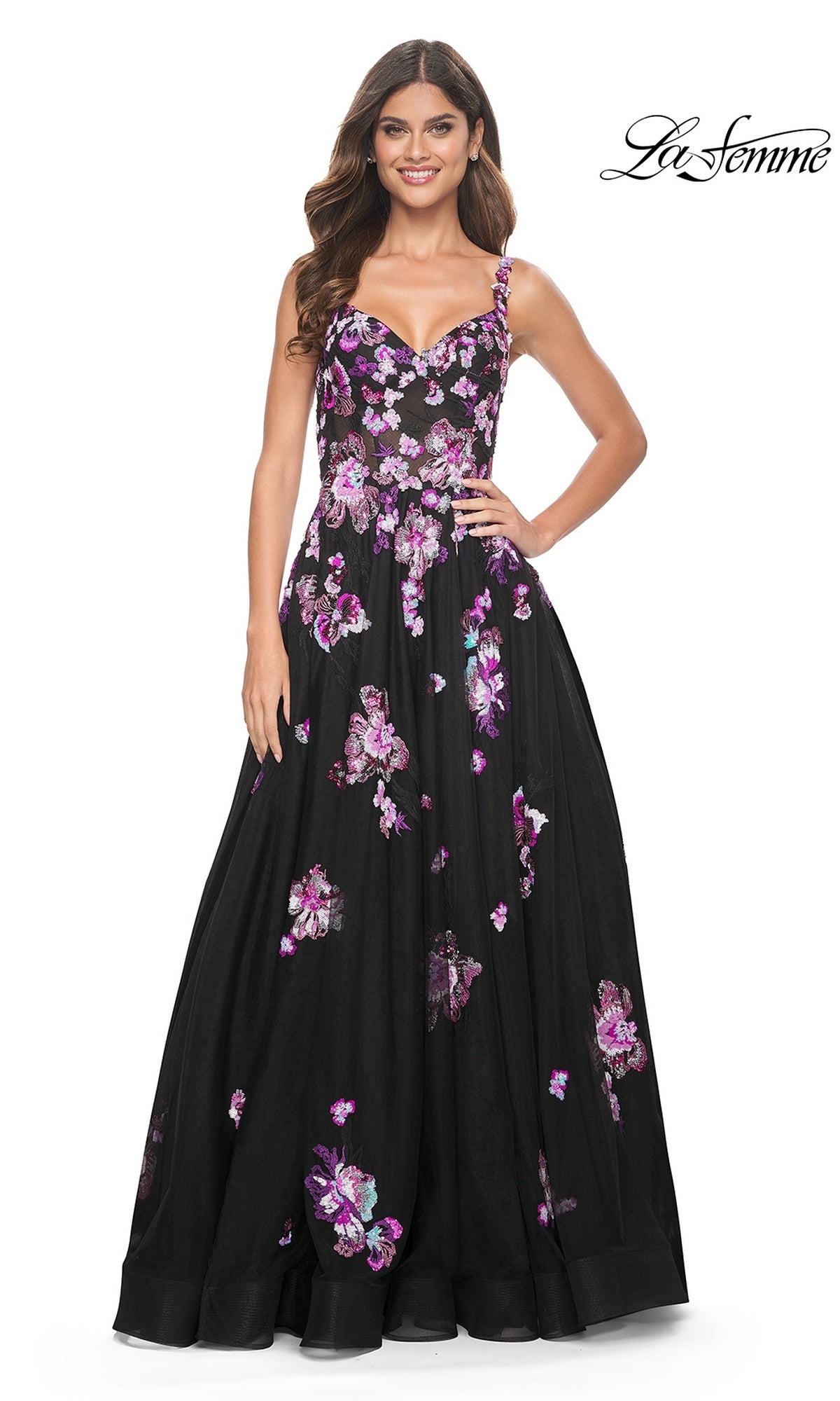 A woman smiles with one hand on her hip, wearing the La Femme Purple-Floral Long Black Prom Dress 32030, featuring elegant pink and purple sequin flower patterns.